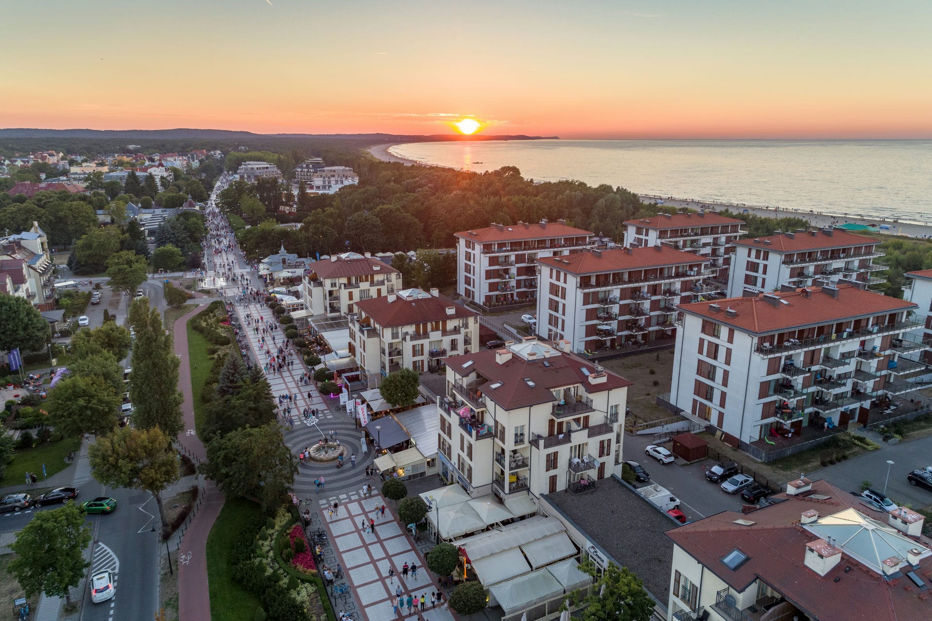 Nadmorskie miasto z deptakiem, hotelami i plażą nad zatoką o zachodzie słońca